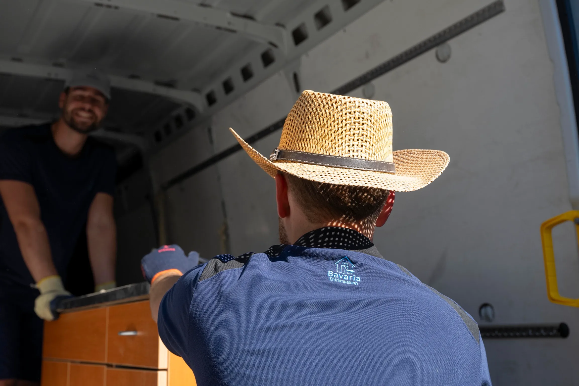 Zwei Mitarbeiter heben einen Schrank in den Transporter