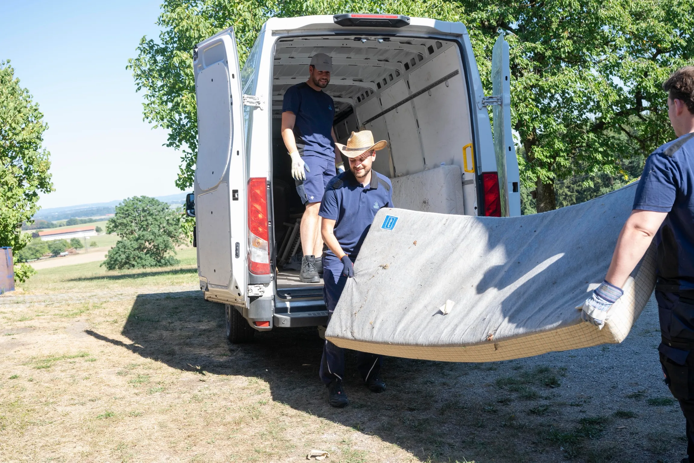 Das Team lädt eine ausgediente Matratze in den Transporter